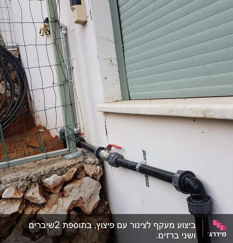 צינור מים שחור עם ברז על קיר חיצוני